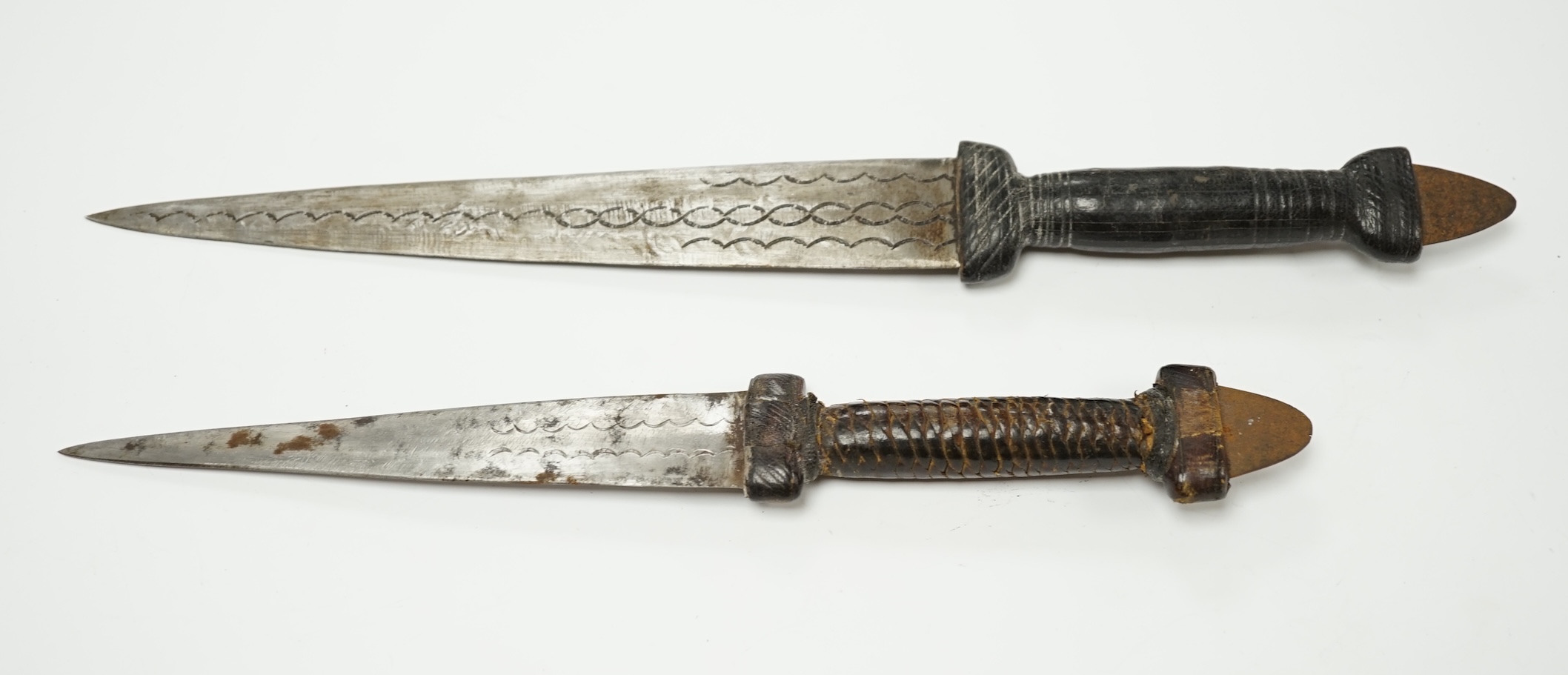 Two African Tuareg arm daggers, with leather grips and leather sheaths, longest blade 20cm. Condition - good